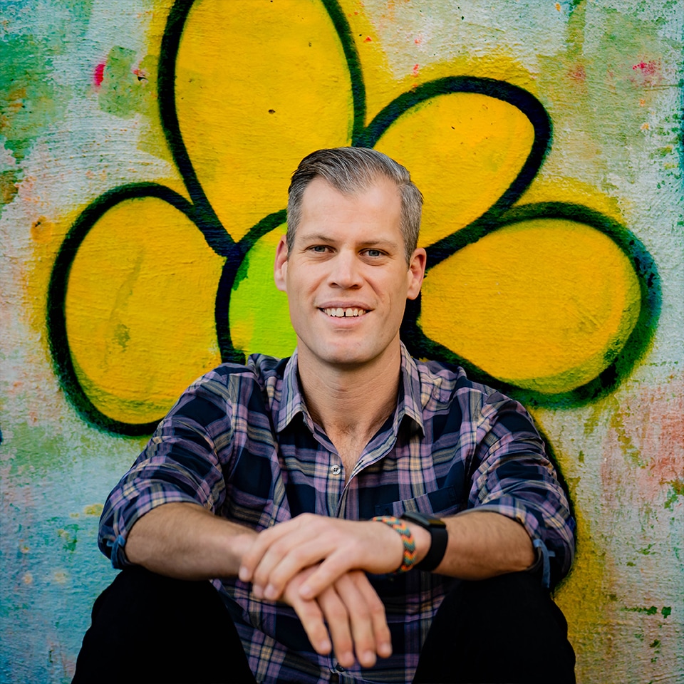 Portrait of Basil Camu by a wall with a flower painting